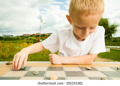 Draughts Board Game. Little Boy Clever Child Kid Playing Checkers Thinking, Outdoor In The Park. Childhood And Development