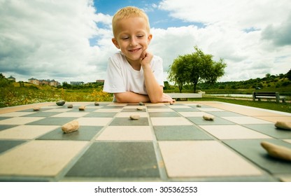 Draughts Board Game. Little Boy Clever Child Kid Playing Checkers Thinking, Outdoor In The Park. Childhood And Development