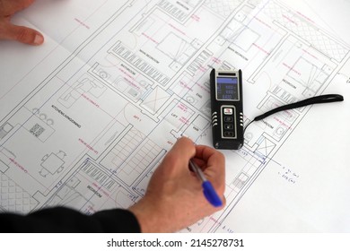 A Draughtsman Surveying Building And Taking Measurements With A Laser Measuring Tool. 