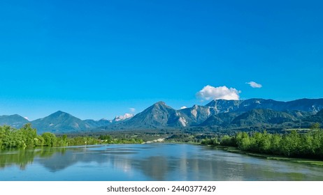 Drava river with panoramic view of majestic mountain ridges of Karawanks and Julian Alps, Carinthia, Austria, Europe. Idyllic landscape in Austrian Alps. Natural wilderness in summer. Wanderlust - Powered by Shutterstock