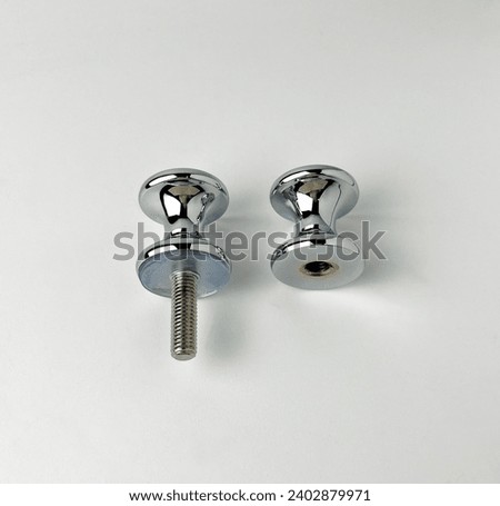 Drawer, cabinet, or cardboard chrome stainless steel knob accessories. Industrial object photography isolated on plain white background.