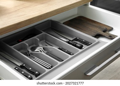 Drawer with set of knives and boards in kitchen