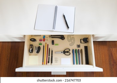 drawer with tools and accessories for drawing and office, with copybook and pen on desk