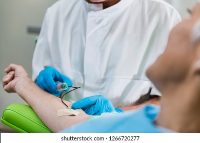Drawing Blood for Platelet Rich Plasma face treatment.  Doctor's hand in blue surgical glove drawing blood for PRP face cosmetics treatment. 