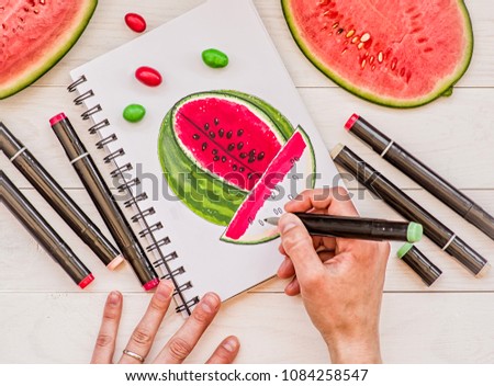 drawing a bright watermelon sketch with markers on wooden background