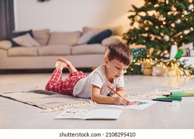 Drawing by using pencil. Little boy is in room with christmas tree is on the floor.