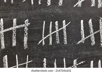 Drawing counting tally chart with chalk, marks in groups of five, counting days