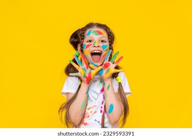 Drawing and creativity for children. A little girl shows her palms painted with multicolored paints. A child smeared in paint. Yellow isolated background. - Powered by Shutterstock