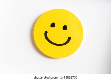 Drawing of a happy smiling emoticon on a yellow paper and white background. - Shutterstock ID 1495882730