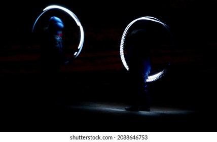 Drawing With Light At Night With Long Exposure. Spiral Circles And Wavy Lines Using Pyrotechnic Sparklers Led Lights. White Color Effect Hand Movements Of Children, Lightsabers, Sabre