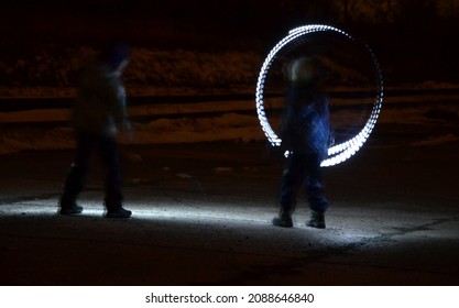 Drawing With Light At Night With Long Exposure. Spiral Circles And Wavy Lines Using Pyrotechnic Sparklers Led Lights. White Color Effect Hand Movements Of Children, Lightsabers, Sabre