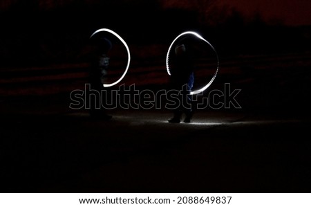 drawing with light at night with long exposure. spiral circles and wavy lines using pyrotechnic sparklers led lights. white color effect hand movements of children, lightsabers, fencing