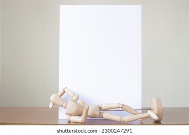 A drawing mannequin lying in front of a blank vertical sheet for on a table