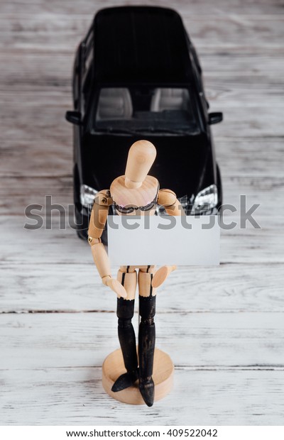 drawing model human female\
manikin dummies wooden doll holding a white empty plate with space\
for your text on a background of a toy car,  on white wooden\
vintage table