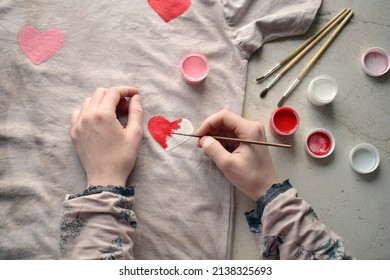 Drawing Red And Pink Heart On Clothes. Painting On A Gray Fabric Cloth With A Paintbrush. Creating Your Own T-shirt Workshop