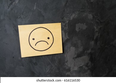 Drawing Of Sad Face On Sticky Note Paper On Cement Wall Texture Background, Loft Style