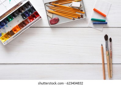 Drawing tools  stationary supplies  workplace artist  Watercolor paints   blank paper white wooden desk  top view  flat lay  copy space