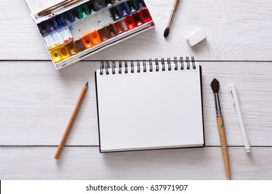 Drawing Tools, Stationary Supplies, Workplace Of Artist. Watercolor Paints And Blank Paper On White Wooden Desk, Top View, Flat Lay, Copy Space