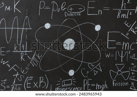 Drawn atomic structure and physics formulas on black chalkboard