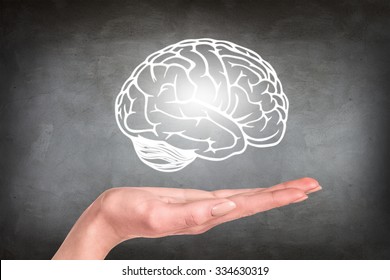 Drawn brain hovered over the human hand on the gray wall background