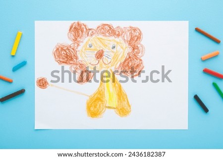 Drawn cute smiling lion shape on white paper. Colorful wax crayons on light blue table background. Pastel color. Closeup. Children drawing art. Top view.