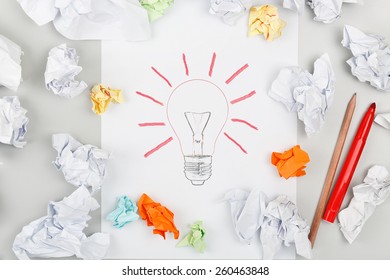 drawn lightbulb surrounded by crumpled pieces paper