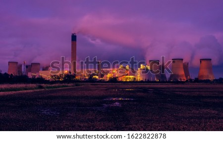 Drax, North Yorkshire, UK.  A cold winter's night in January with the bright lights of a power station reflected in a waterlogged farmer's field.  Horizontal.  Space for copy.