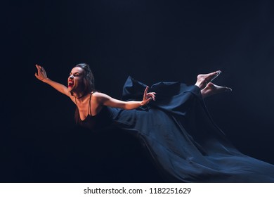 dreadful woman in vampire costume flying on dark background 