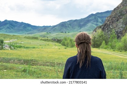 Dreadlocks woman looking at mountain range. Rear view of hipster tourist woman. Travel freedom concept.