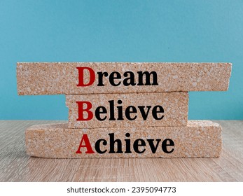 Dream Believe Achieve symbol. DBA acronym on brick blocks with letters. Beautiful blue background, wooden table. Concept image of Business Acronym DBA as Dream Believe Achieve - Shutterstock ID 2395094773