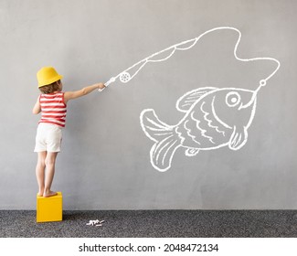 Dream big! Happy kid draws a chalk fish on the wall. Children imagination and summer vacation concept 