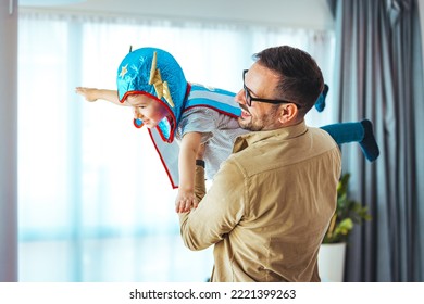 Dream big. Loving father helps his son fly like a superhero. Boy play fly with his dad at home. Cheerful familyare having fun together. Father holding son in superhero costume flying at home  - Powered by Shutterstock