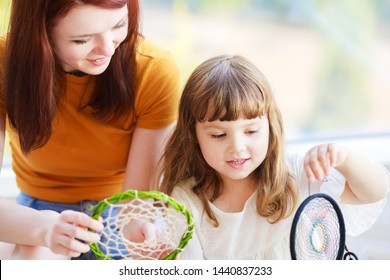 Dream catcher creation. Young woman, mother, sister or nanny making dream hunter with little girl. Workshop, hobby, handicraft, creativity concept. Family activity - Powered by Shutterstock