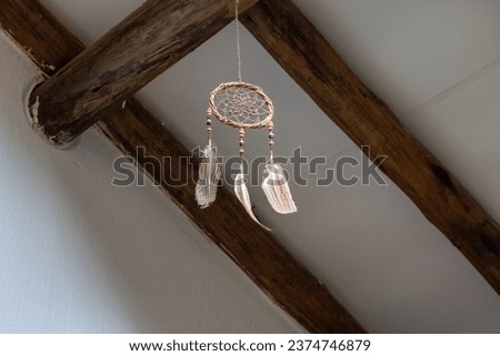 A dream catcher hangs from a ceiling with large wooden beams