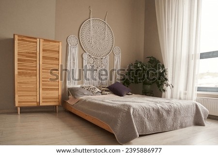 A dream catcher woven with the technique of knotted weaving, a macrame above the bed in the bedroom. Living room interior with space to copy. High quality photo