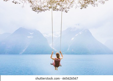 dream concept, beautiful young woman on the swing in fjord Norway, inspiring landscape