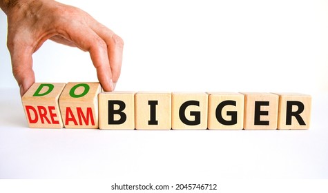 Dream And Do Bigger Symbol. Businessman Turns Wooden Cubes And Changes Words Dream Bigger To Do Bigger. Business And Dream And Do Bigger Concept. Beautiful White Background, Copy Space.