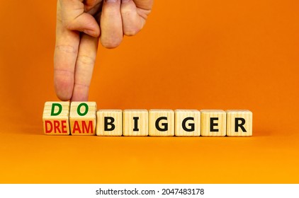 Dream And Do Bigger Symbol. Businessman Turns Wooden Cubes And Changes Words Dream Bigger To Do Bigger. Business And Dream And Do Bigger Concept. Beautiful Orange Background, Copy Space.