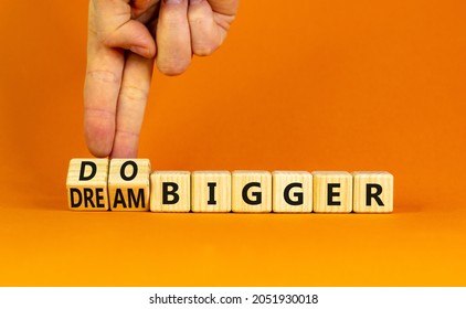 Dream And Do Bigger Symbol. Businessman Turns Wooden Cubes And Changes Words Dream Bigger To Do Bigger. Business And Dream And Do Bigger Concept. Beautiful Orange Background, Copy Space.