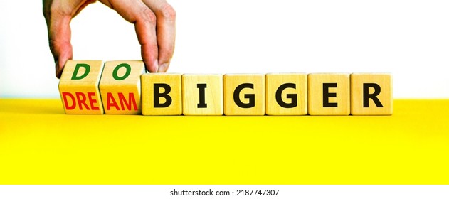 Dream And Do Bigger Symbol. Businessman Turns Wooden Cubes And Changes Words Dream Bigger To Do Bigger. Business And Dream And Do Bigger Concept. Beautiful White Background, Copy Space.