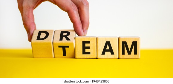 Dream team symbol. Businessman turns cubes and changes the word 'dream' to 'team'. Beautiful yellow table, white background. Business and dream team concept, copy space.