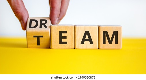 Dream team symbol. Businessman turns the cube and changes the word 'dream' to 'team'. Beautiful yellow table, white background. Business and dream team concept, copy space.