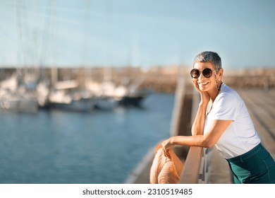 Dream Vacation. Happy Senior Lady Posing With Sunglasses Holding Summer Straw Hat, Standing At Sea Pier With Yachts. Relaxed Tourist Woman Enjoying Holidays And View At Marina Dock. Free Space - Shutterstock ID 2310519485