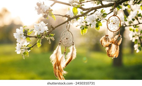 Dreamcatcher hanging on blooming tree in wind at springtime. Spirituality and ritual ornament for good dreaming - Powered by Shutterstock