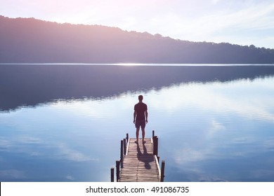 dreamer, silhouette of man standing on the lake wooden pier at sunset, human strength, psychology concept