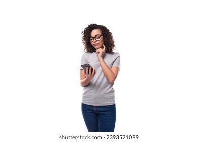 dreaming caucasian young brunette woman with shoulder-length curly hair looks into a smartphone - Shutterstock ID 2393521089