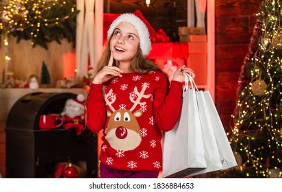 Dreaming. Holiday Gift Shopping. Christmas Is Here. New Year Winter Vacation. Kid Reindeer Sweater And Santa Hat. Shopping Packages For Family. Small Shopaholic. Child Smile With Paper Bags.