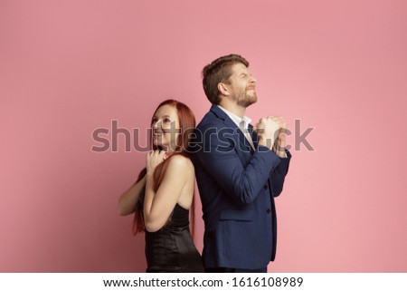 Dreaming together. Valentine's day celebration, happy caucasian couple isolated on coral studio background. Concept of human emotions, facial expression, love, relations, romantic holidays.