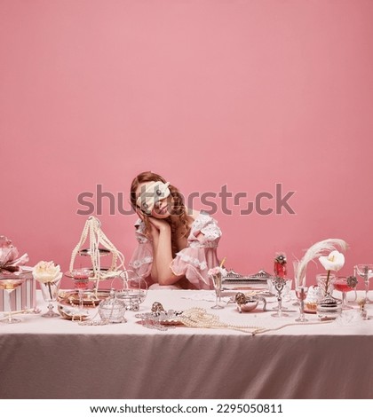 Dreaming young princess. Portrait of adorable queen wearing dress and sleeping mask sitting at table and sleep over pink studio background. Concept of medieval, beauty, fashion, mood, daily routine