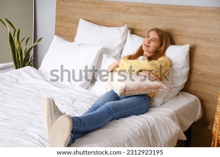 Dreaming young woman lying on bed at home